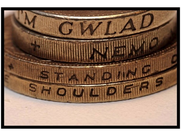 Photo of the edge of coins, with the words *Standing On* and *Shoulders* visible